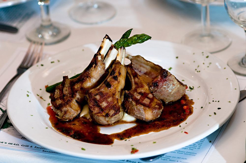 a white plate topped with lamb chops and asparagus on a table .