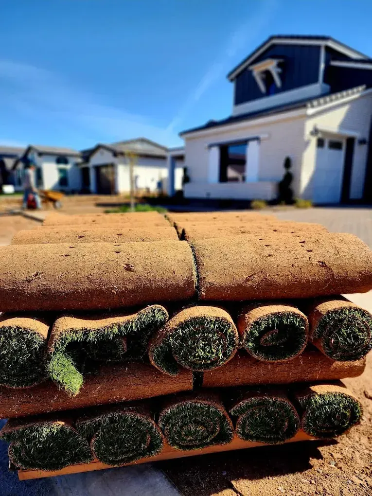 A stack of grass rolls in front of a house