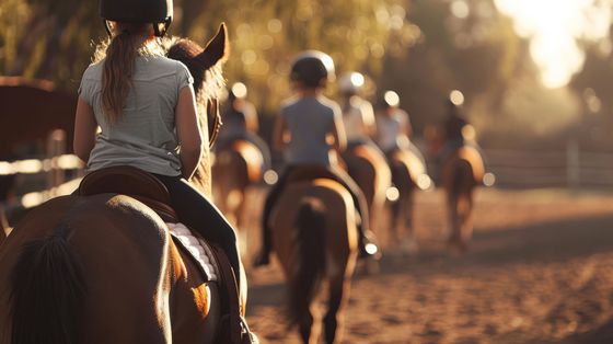 A group of people are riding horses down a dirt road.