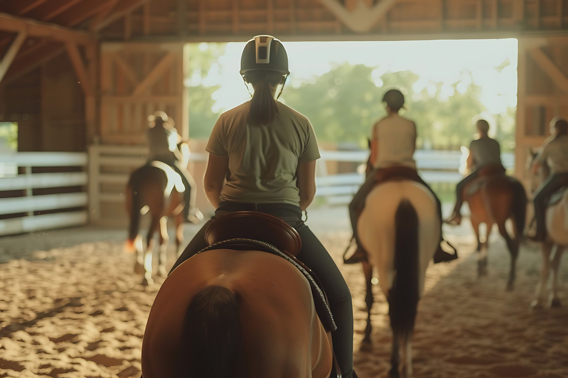 A group of people are riding horses in a barn.