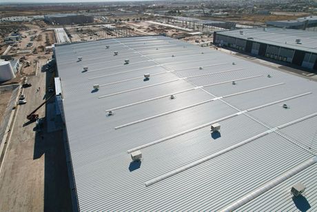 Aerial view of large, corrugated metal warehouse roof with vents and pipes.