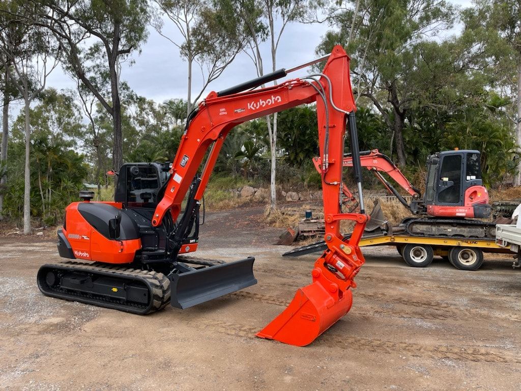 A Yellow Excavator is Parked in a Dirt Field — Eddy’s Excavations & Bobcat Hire In Gladstone, QLD
