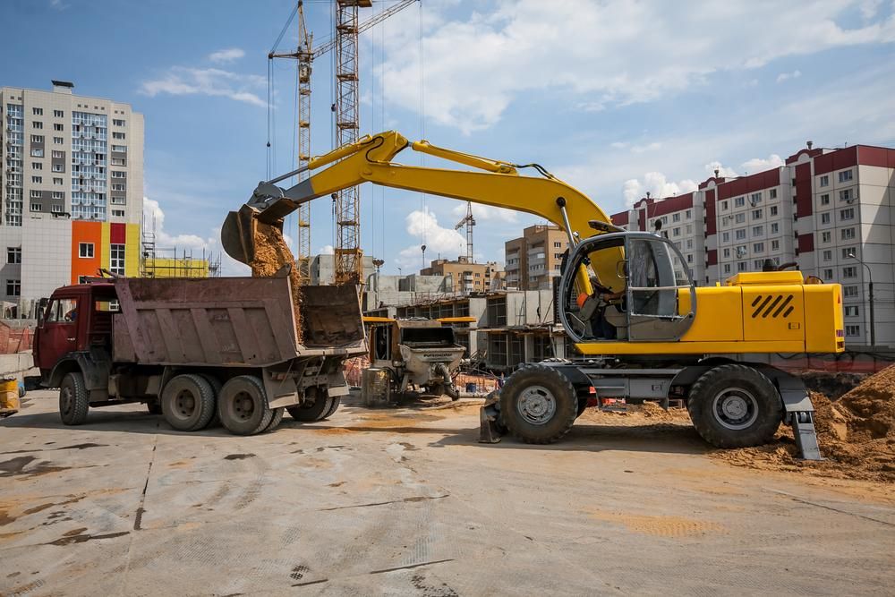 Excavator is Loading Dirt Into a Dump Truck at a Construction Site — Eddy’s Excavations & Bobcat Hire In Tannum Sands, QLD