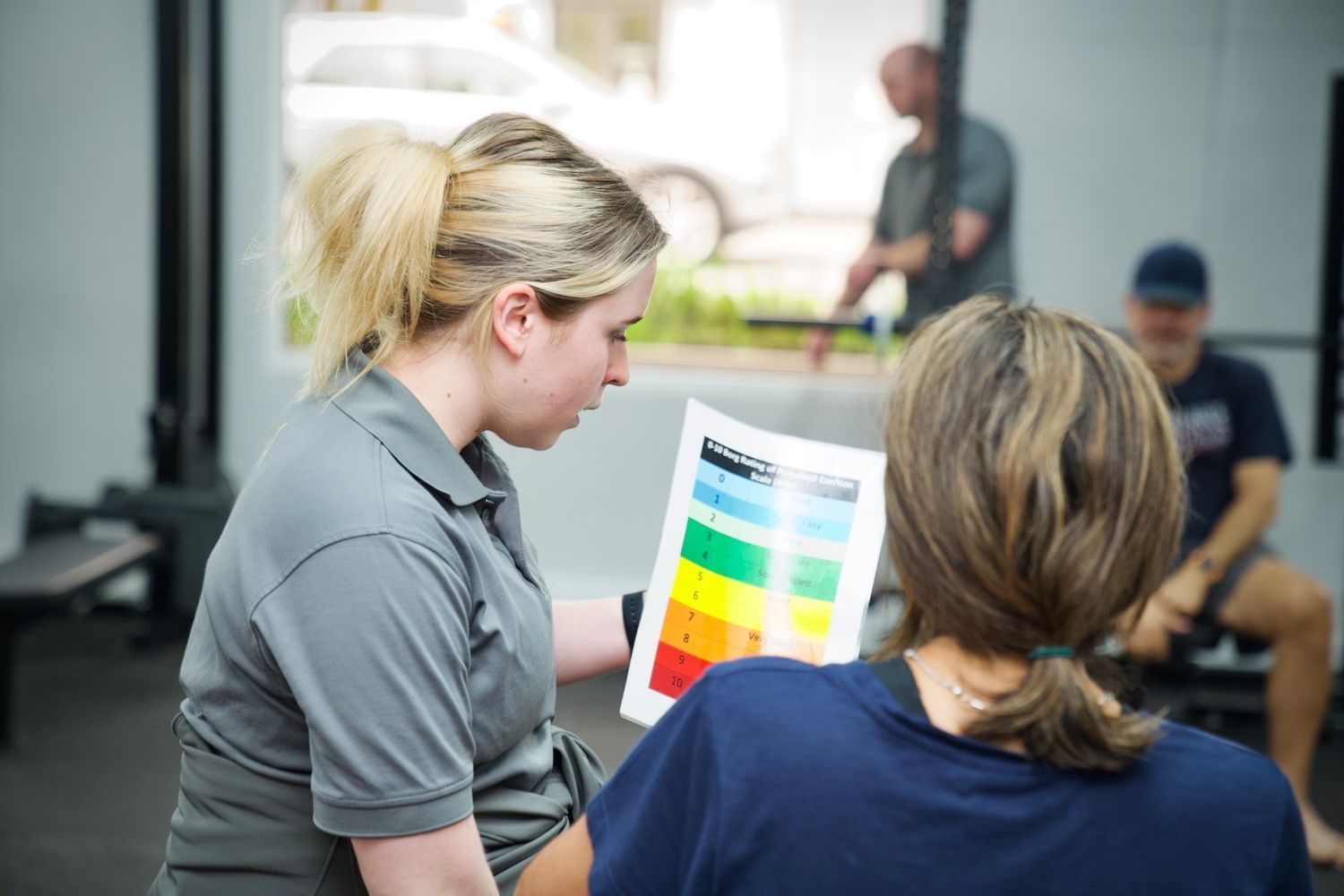 A woman is talking to another woman while holding a piece of paper.