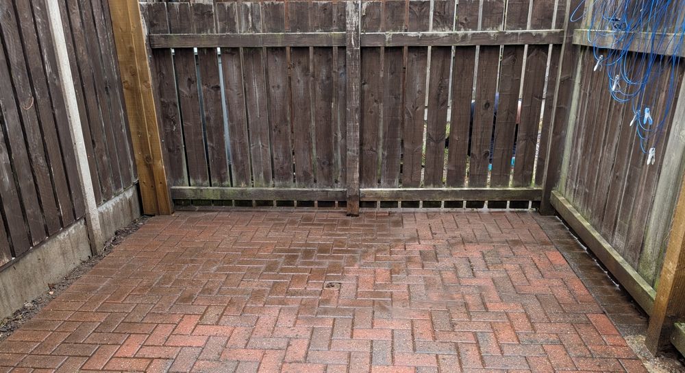 Brick patio enclosed by wooden fences and gate. after clean up