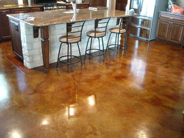 Polished concrete floor in shades of brown, reflecting kitchen island with stools.