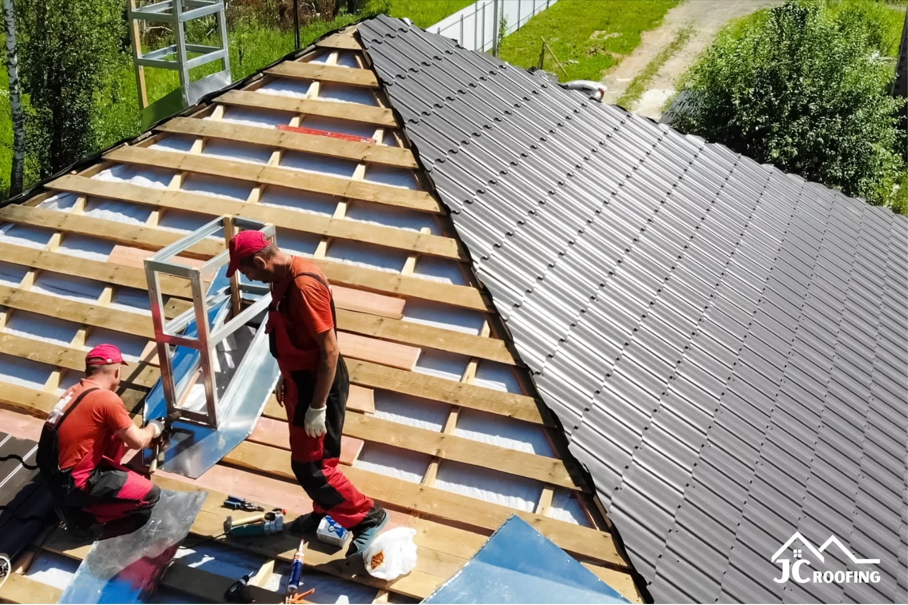 Roofers installing skylight on a sloped roof with gray shingles and exposed wooden battens
