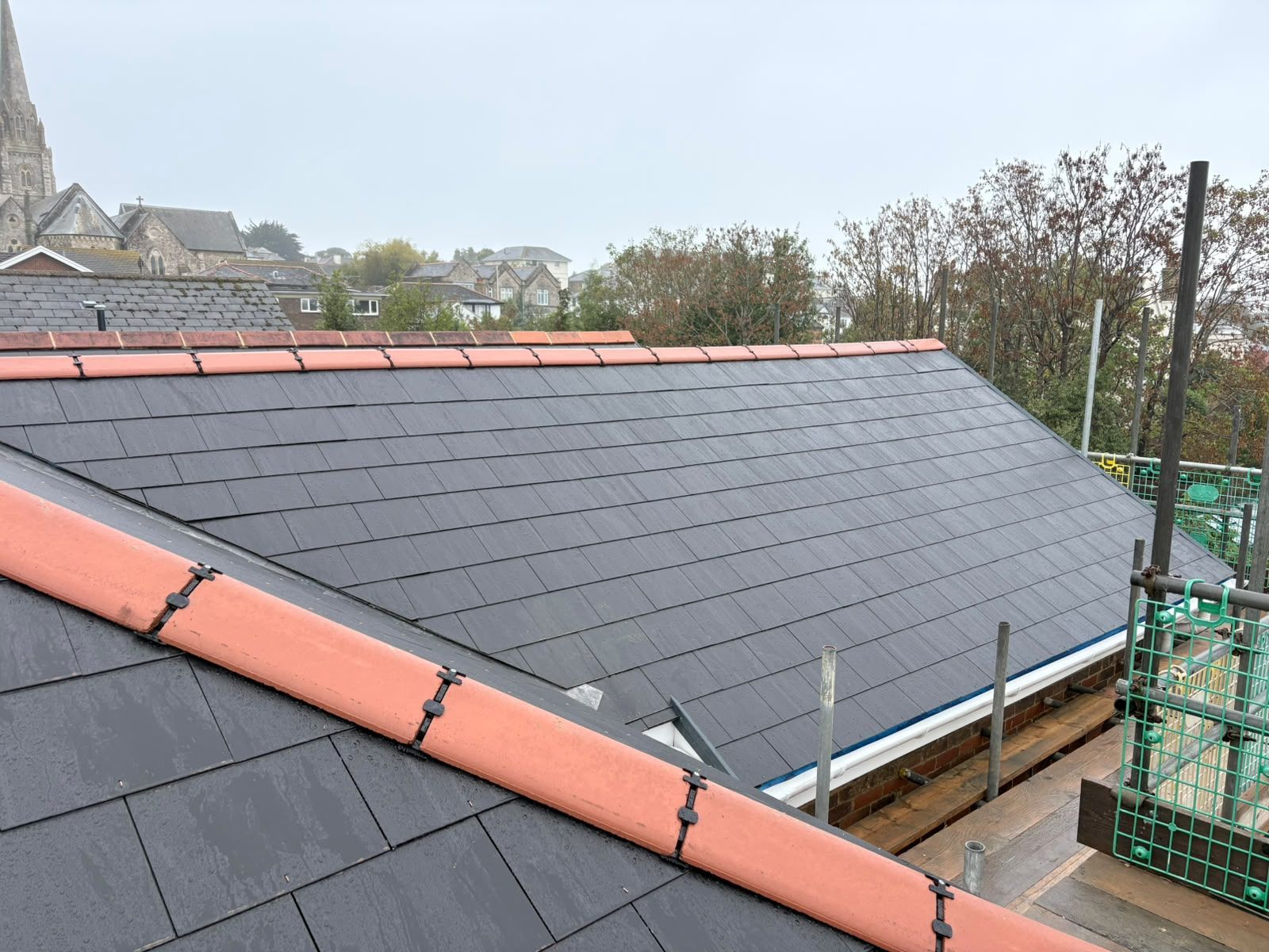 Slate roof under construction with red ridge tiles and scaffolding on the right