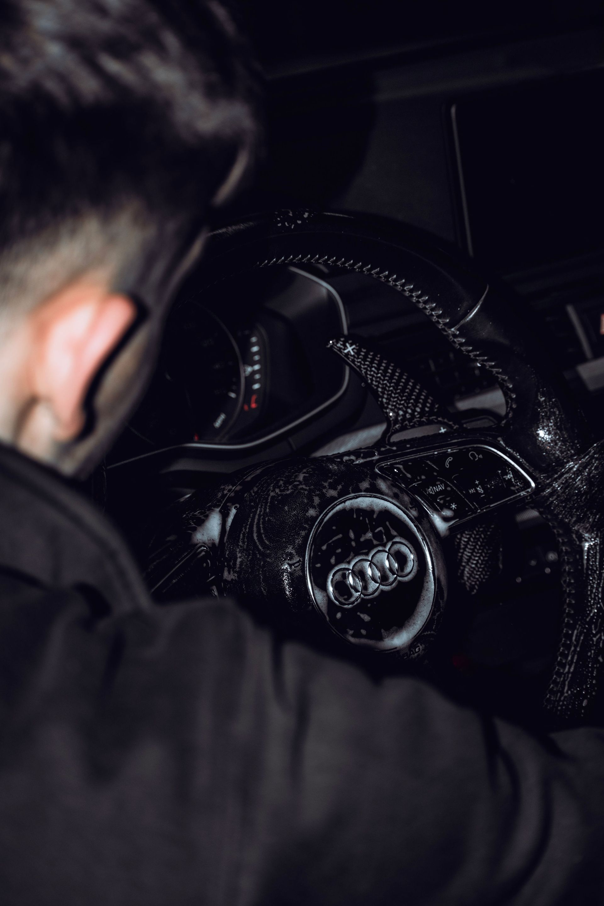 Person in dark clothing driving a car at night, with dashboard and steering wheel visible