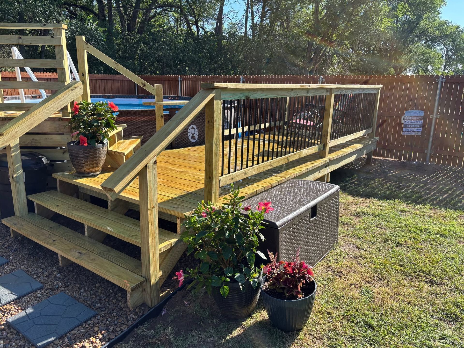 Wooden deck ramp with railings and potted flowers in a sunny backyard
