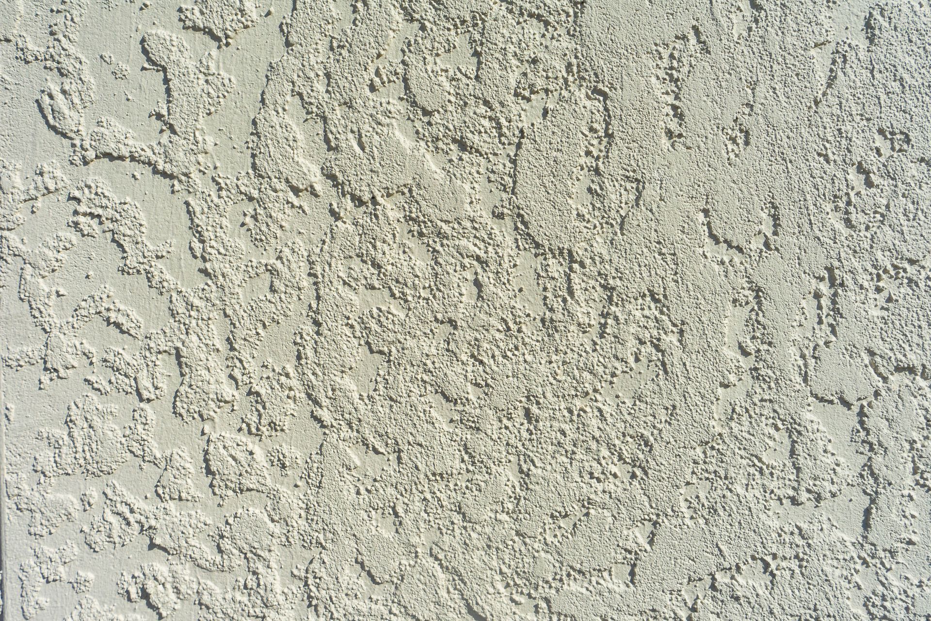 Close-up of rough, light beige stucco wall texture