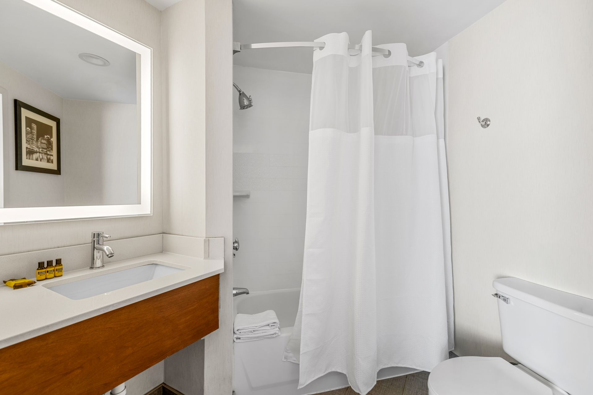 Modern white bathroom with vanity, mirror, toilet, and shower curtain