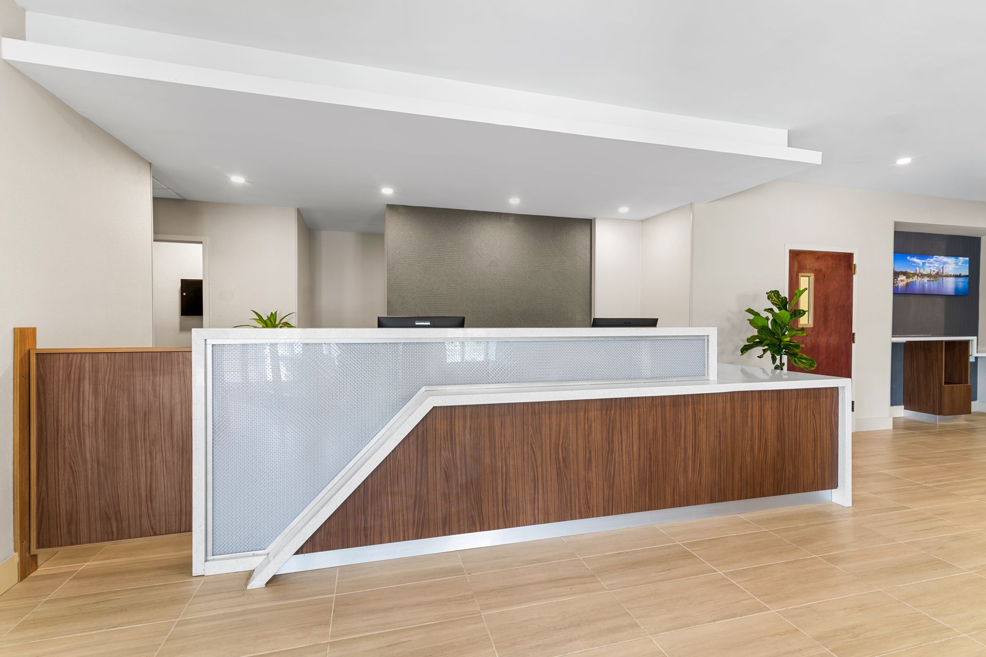 Modern hotel reception desk with wood and frosted glass in a bright lobby