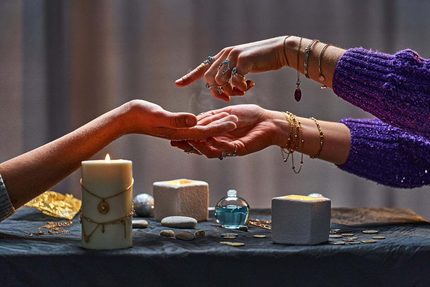 A person's palm being read by another, with candles and accessories on a table.