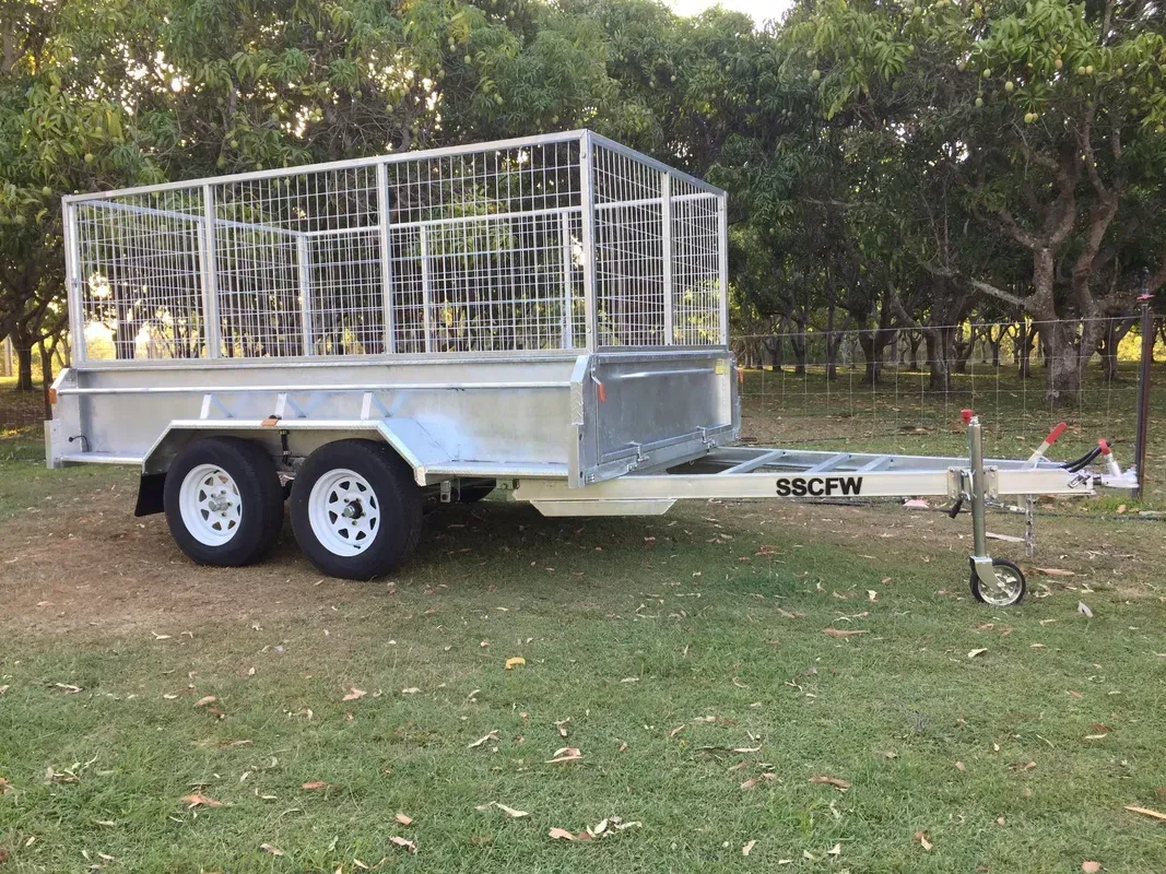 Two-axle livestock trailer with white mesh sides parked on grass, hitched to a tow bar. — SSCFW Trailers In Mareeba, QLD