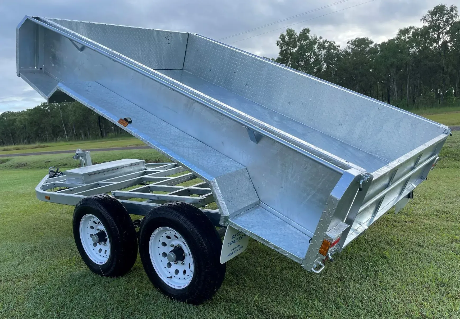 Silver Dump Trailer with Raised Bed, Dual Axles, Parked on Grass Outdoors — SSCFW Trailers In Mareeba, QLD