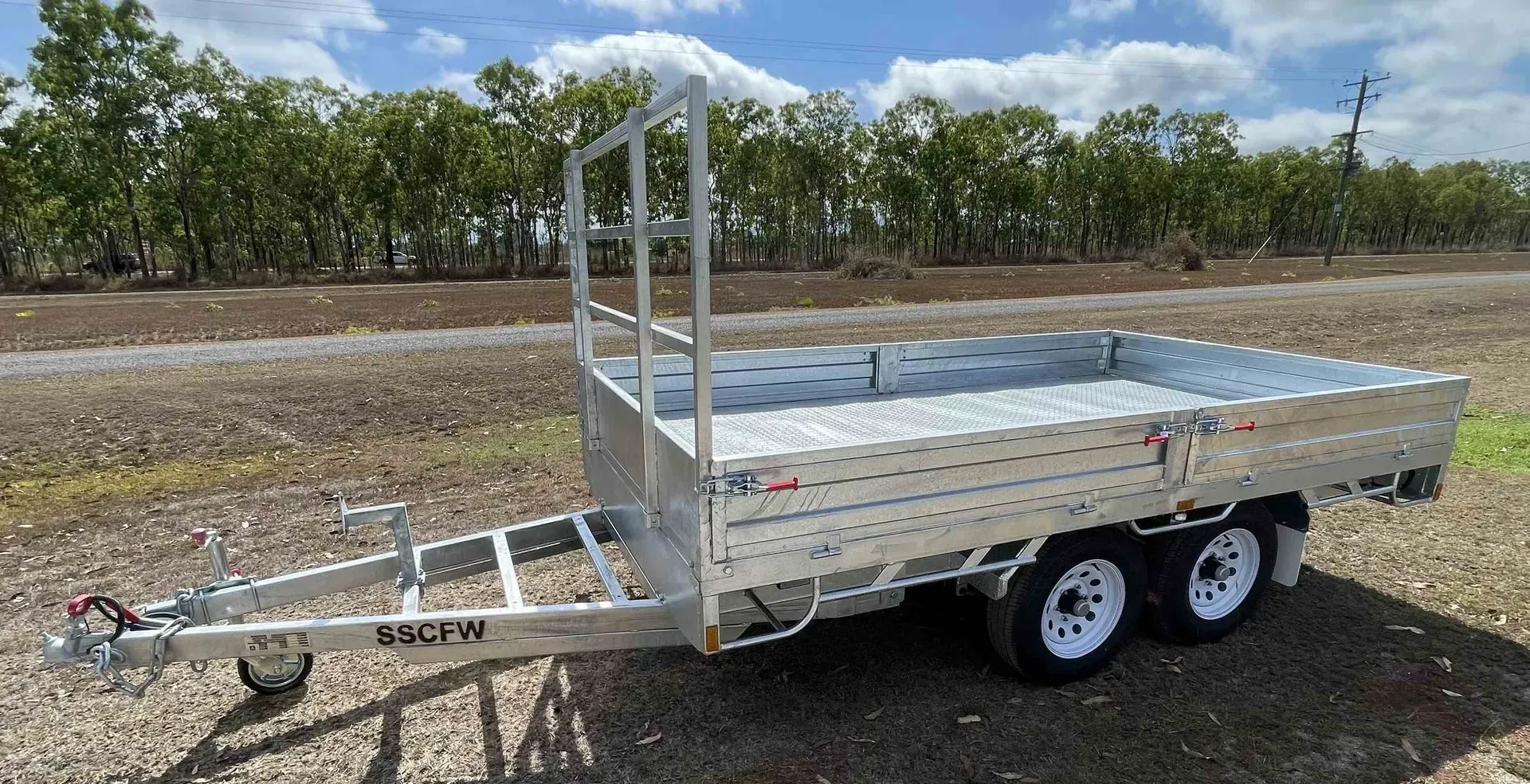Silver Utility Trailer with Mesh Sides and Dual Axles Parked on Dirt — SSCFW Trailers In Cassowary Coast, QLD