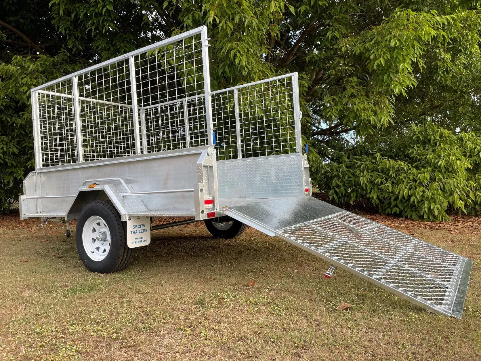 White Utility Trailer with Mesh Sides and A Loading Ramp on Grass — SSCFW Trailers In Mareeba, QLD