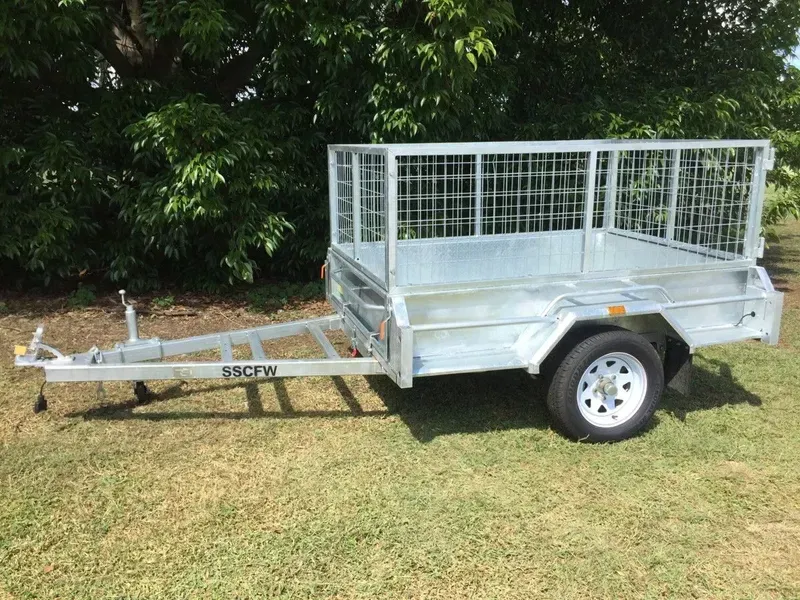 Silver Utility Trailer with Mesh Sides and Front Hitch Parked on Grass by Trees — SSCFW Trailers In Mareeba, QLD