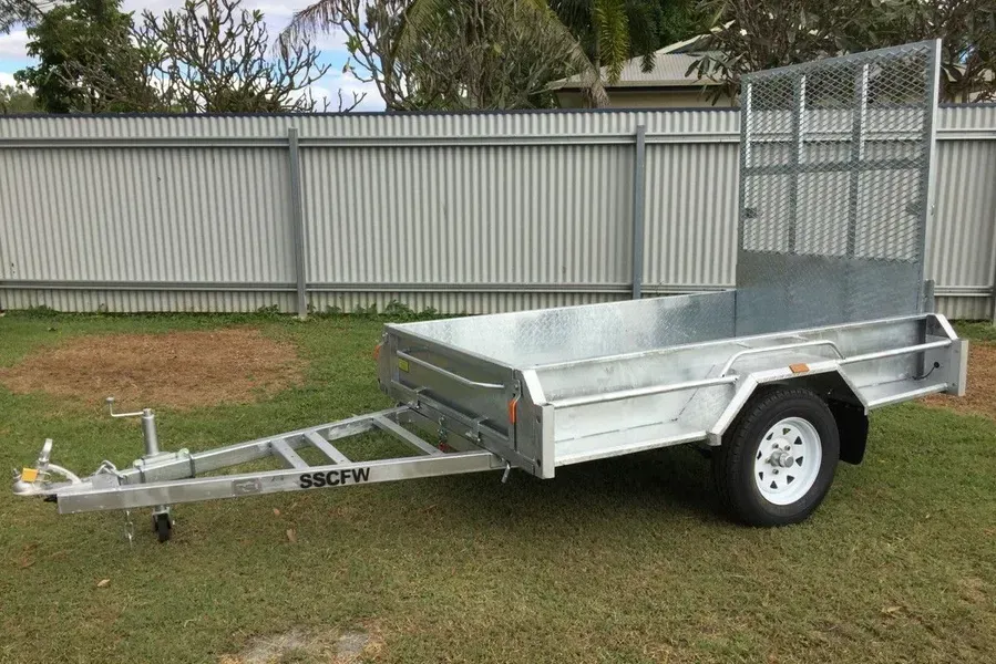 Silver Utility Trailer Parked on Grass Beside a Fence, with Metal Sides and Mesh Ramp Gate — SSCFW Trailers In Mareeba, QLD