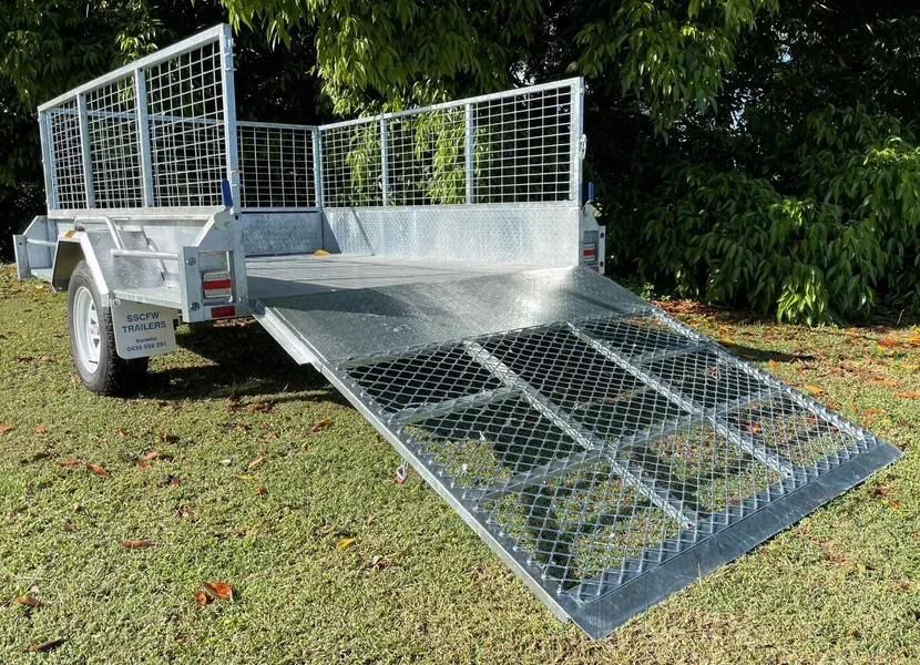 Silver Utility Trailer with Mesh Sides and A Lowered Metal Ramp on Grass Outdoors — SSCFW Trailers In Mareeba, QLD