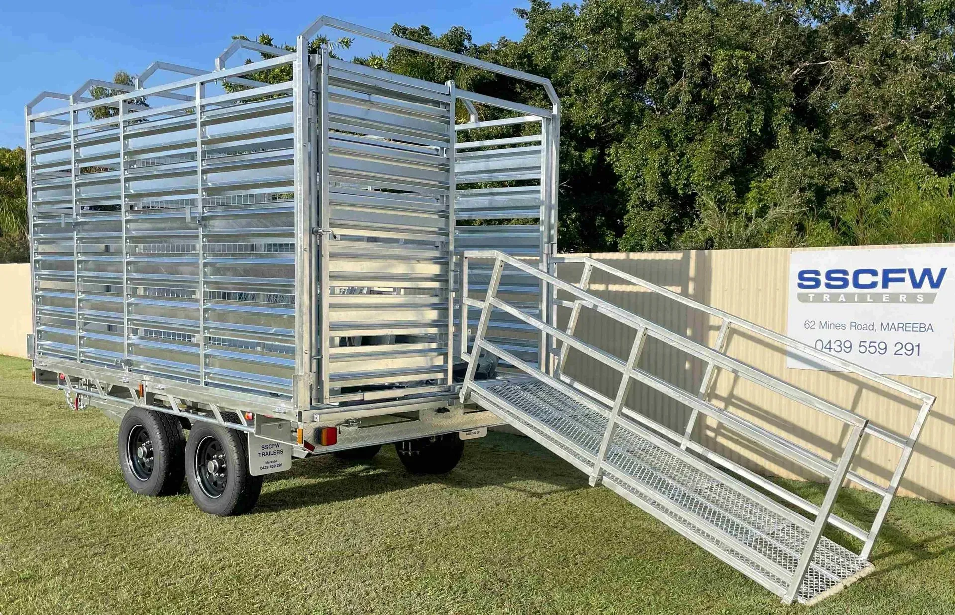 Silver Livestock Trailer with Open Ramp on Grass Beside a Fence and Trees — SSCFW Trailers In Mareeba, QLD