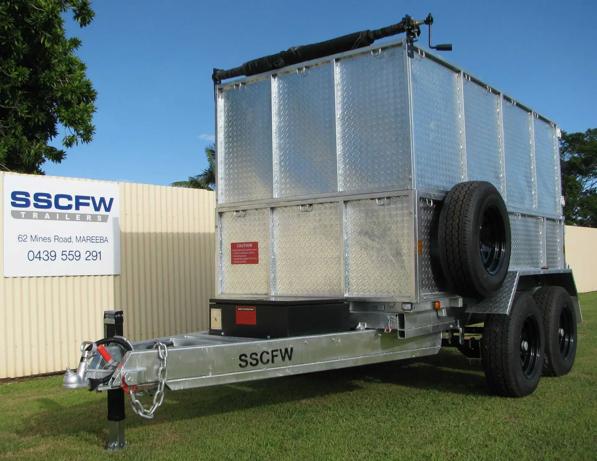 Silver Box Trailer with Black Wheels Parked on Grass Near a Building — SSCFW Trailers In Cassowary Coast, QLD