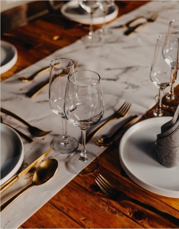 Una mesa de madera con platos y copas de vino sobre ella.