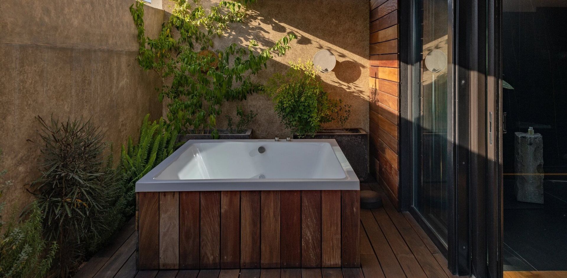 Una bañera está colocada sobre una plataforma de madera al lado de una ventana.