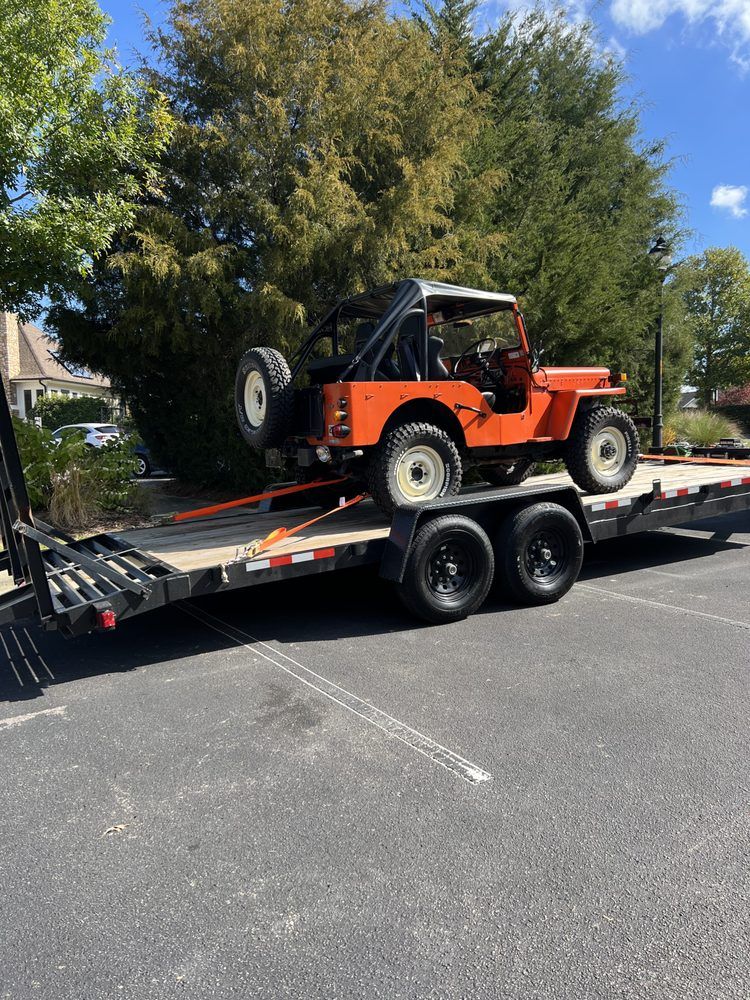 An orange jeep is sitting on top of a trailer.