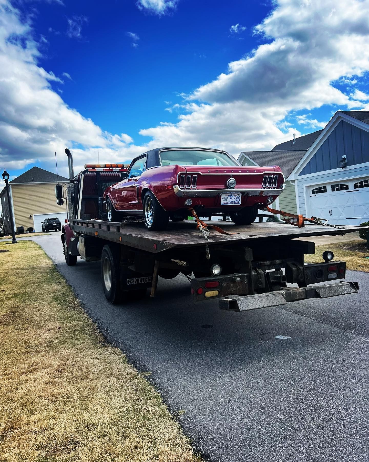 A red car is being towed by a tow truck.