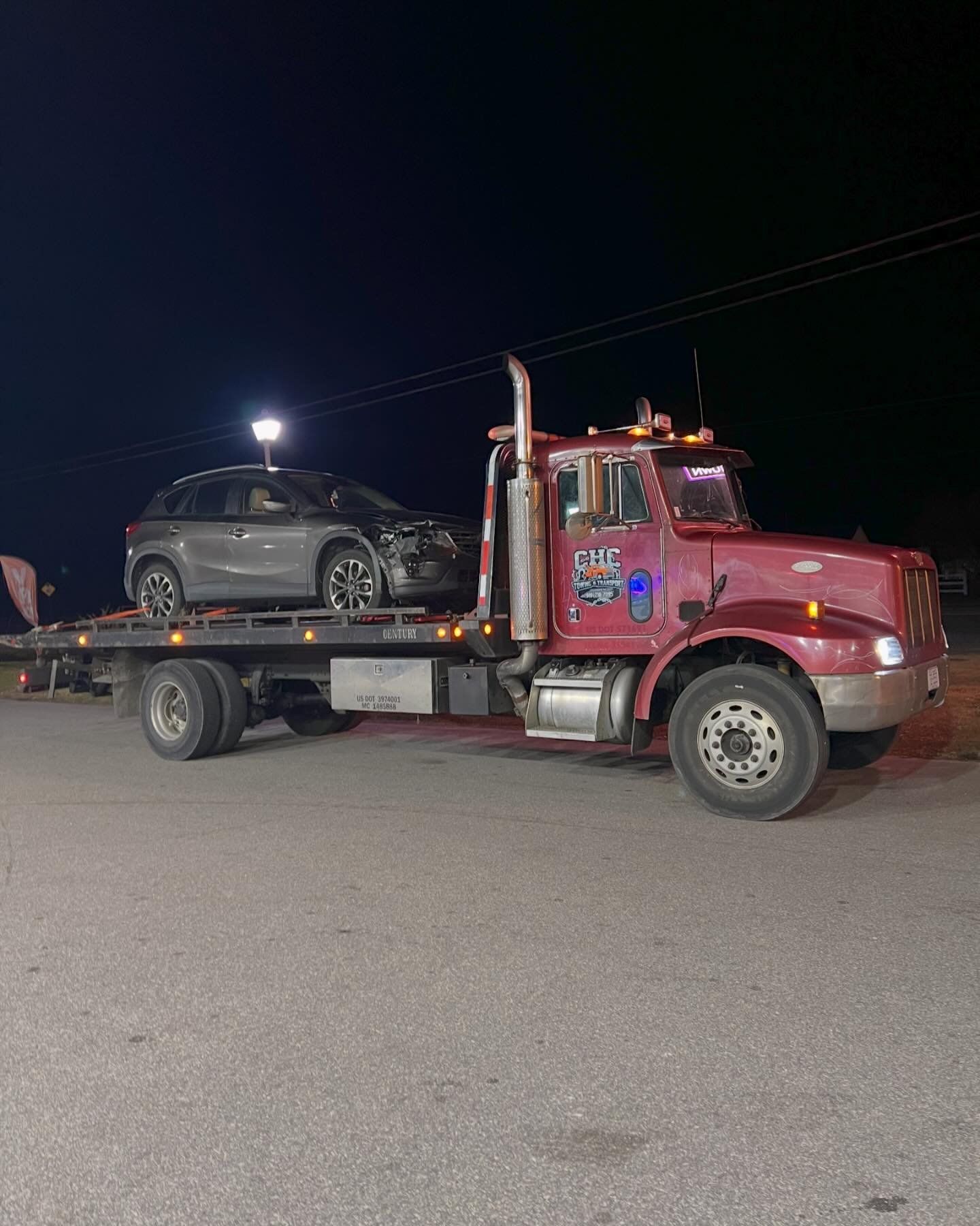 A tow truck is carrying a car on the back of it.
