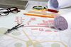Desk with glasses, pens, compass, and ruler on a city map planning layout