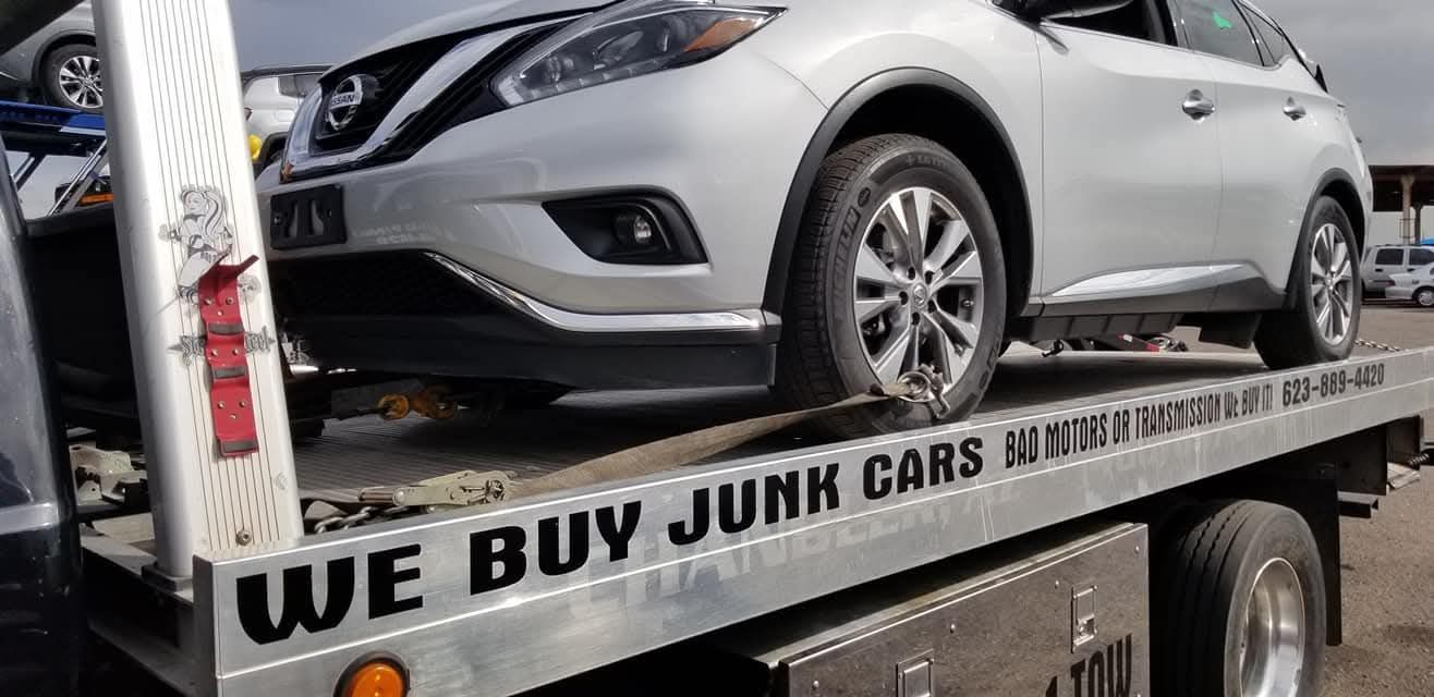 Two people changing a tire on a vehicle. One using a jack to lift the vehicle, the other holding the spare tire.
