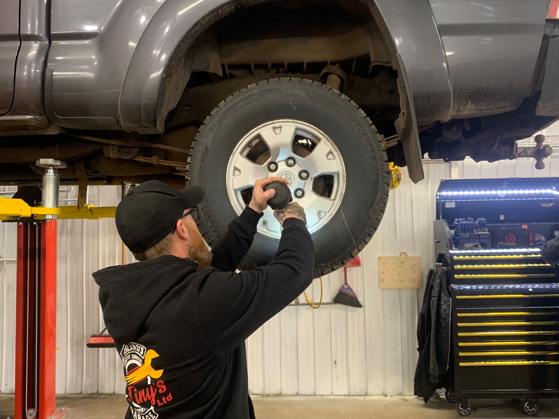 A man is changing a tire on a truck in a garage. | Tiny's Automotive