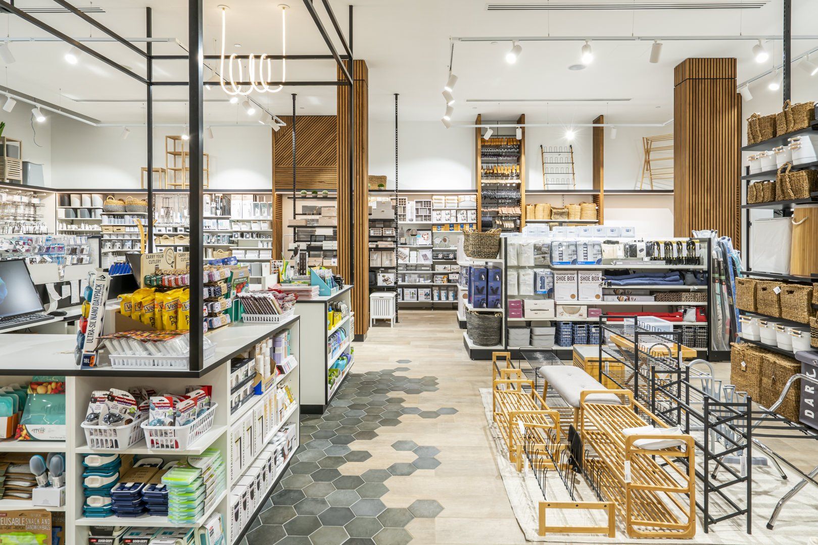 Retail store aisle displaying storage baskets, shelving units, organisers and household storage products arranged on shelves and display racks.