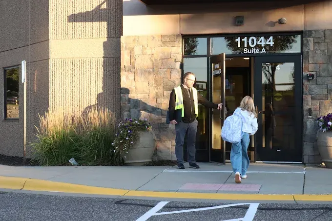 Two people at a glass storefront entrance with the number 11044 above the door.
