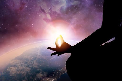 A person is sitting in a lotus position with their hands in front of the earth.