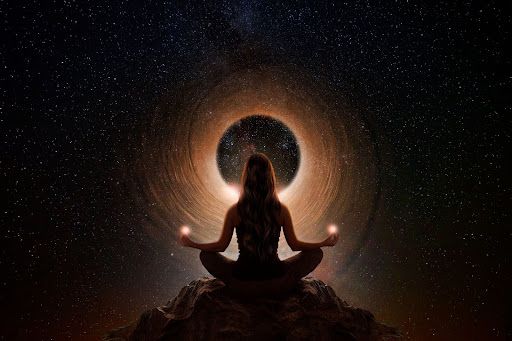 A woman is sitting in a lotus position in front of a black hole.