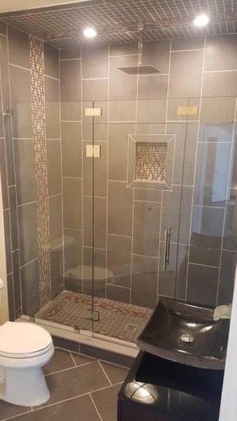 A bathroom with a toilet , sink and walk in shower.