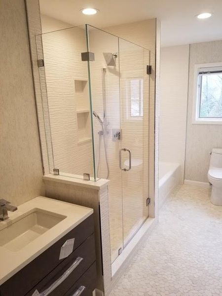 A bathroom with a walk in shower , sink , toilet and window.
