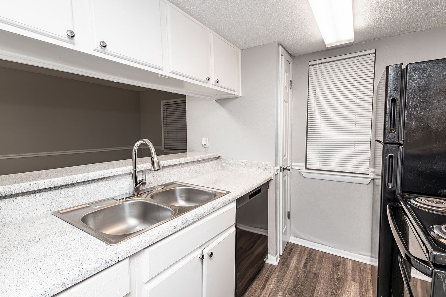 A kitchen with two sinks , granite counter tops and white cabinets.