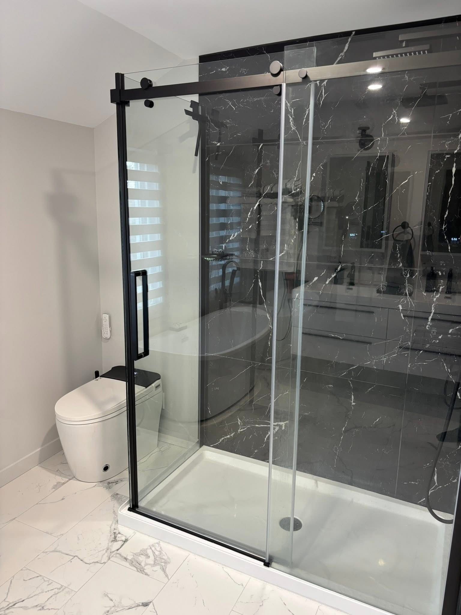 Salle de bains moderne avec douche à l'italienne, cadre noir, receveur de douche blanc et mur d'accent en marbre.