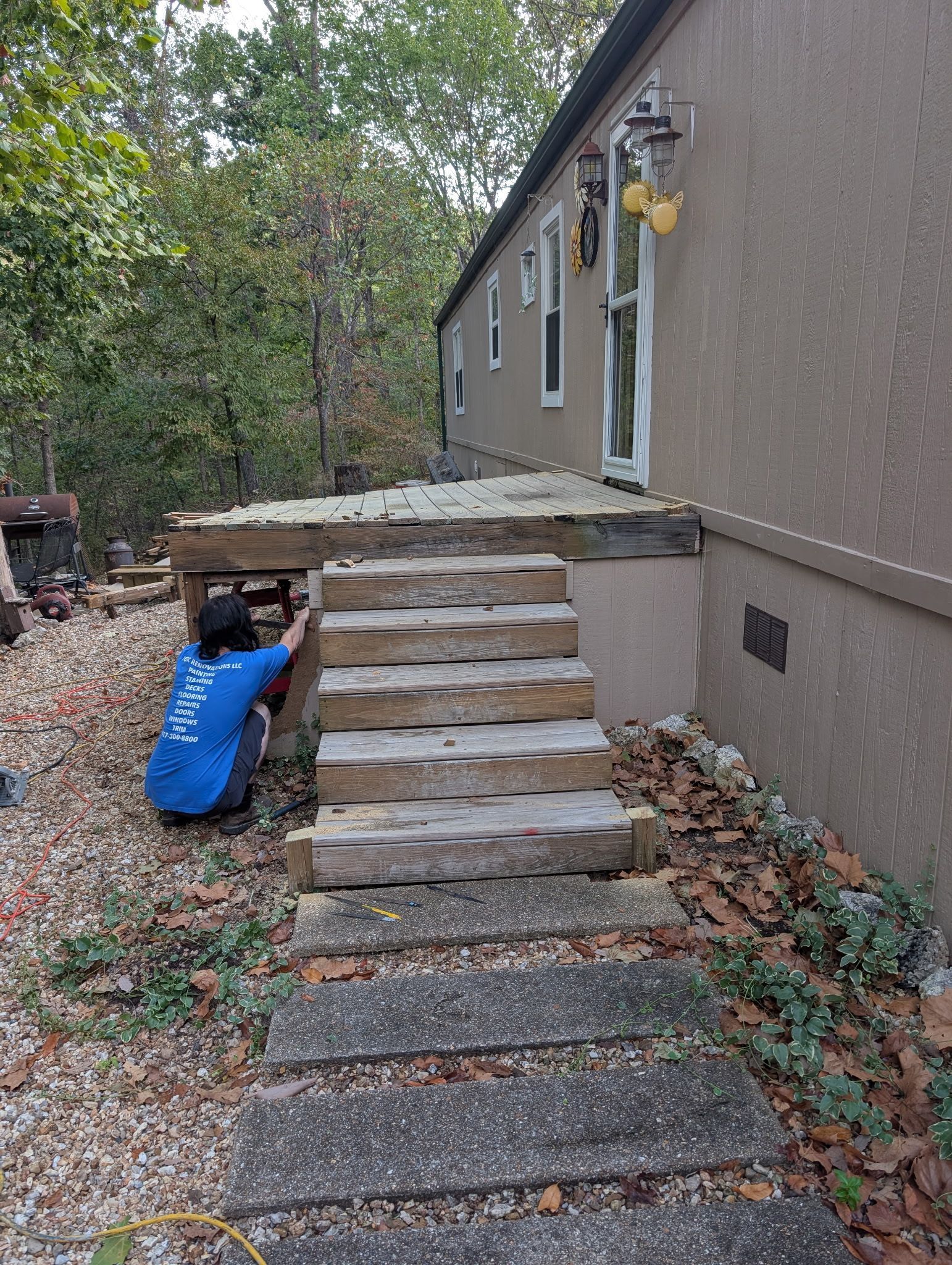 Steep concrete steps leading to a raised porch beside a house, with a blue bag beside the stairway.