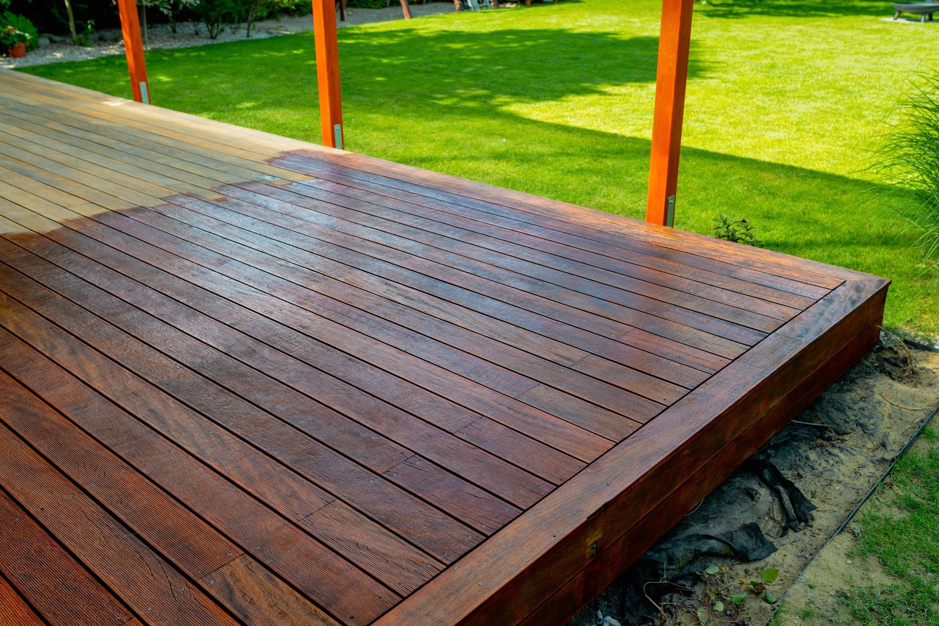 Wooden deck platform beside a green lawn with orange posts and paved walkway