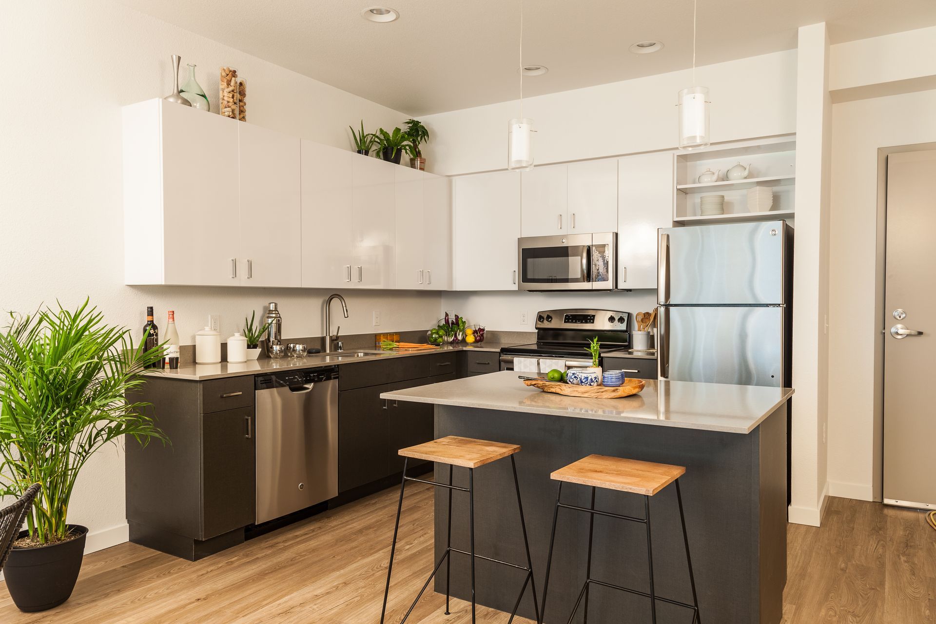 Modern kitchen with white cabinets, stainless steel appliances, and a black island with two stools