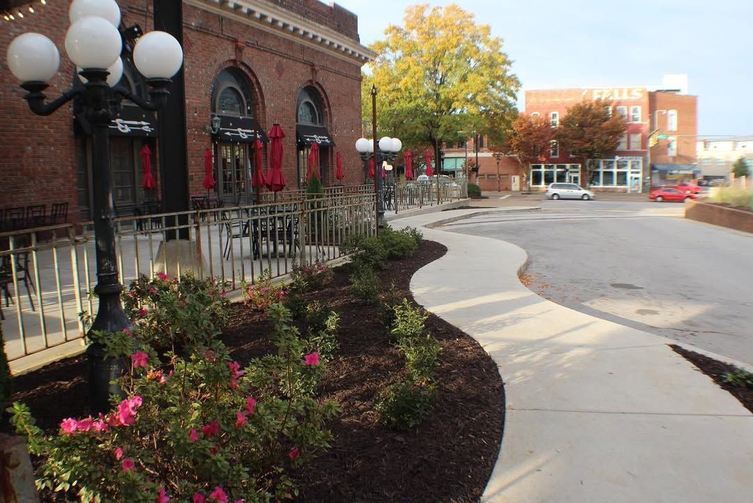 Brick building with outdoor seating, winding sidewalk, and landscaping.