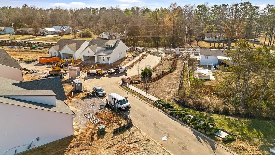 Construction site with houses, vehicles, and equipment; sunny, outdoor setting.