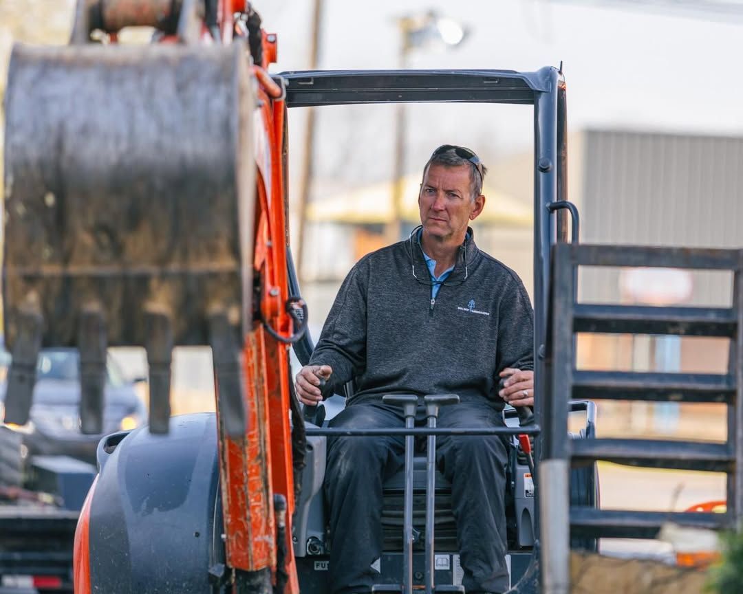 Man operating an orange excavator in an outdoor setting.