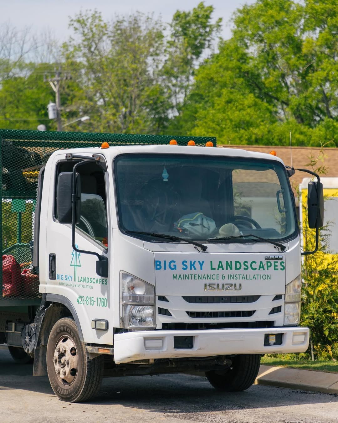 White Big Sky Landscapes truck, green logo, parked outdoors.